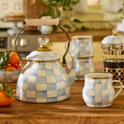 MacKenzie-Childs | Sky Check Tea Kettle, 2 Qt, on a kitchen counter, with a matching mug and wooden handle, part of a serene tea set display.