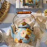 MacKenzie-Childs | Wild Rose Slate Tea Kettle, 2 Qt, featuring floral design, wooden handle, glass lid, on a crocheted doily, surrounded by kitchen linens and decor.