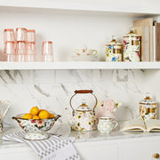 MacKenzie Childs Wildflowers Pink Tea Kettle, 2 QT, features hand-applied floral designs, a wood handle, and a glass-topped lid, showcased in a vintage kitchen setting.