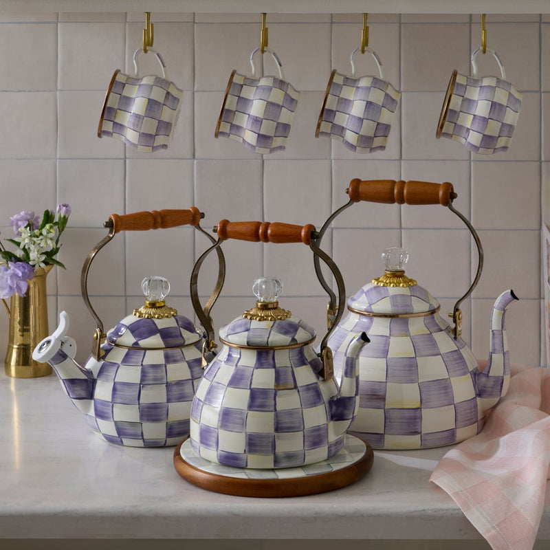 MacKenzie-Childs | Violet Check Tea Kettle, 2 Qt, with hand-painted lavender checks, topped with a crystal-like finial and wood handle on a kitchen countertop display.