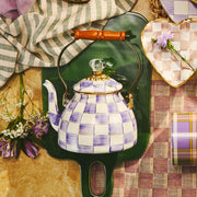 MacKenzie-Childs | Violet Check Tea Kettle, 2 Qt, with a hand-painted checkerboard design, wooden handle, on a green tray with matching dish and mug.