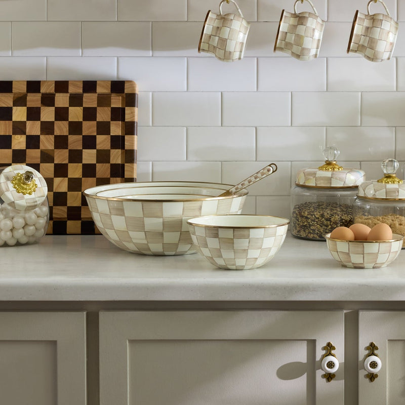 MacKenzie Childs | Mocha Check Small Everyday Bowl displayed on a kitchen counter with matching serveware, highlighting hand-painted checks and bronze rim, ideal for versatile kitchen use.