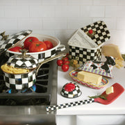 MacKenzie-Childs Courtly Check Recipe Box on a checkered countertop, open with a handwritten card inside, surrounded by fresh tomatoes and matching cookware.