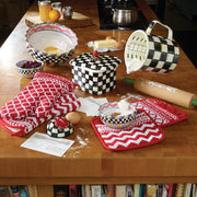 MacKenzie-Childs Courtly Check 7 Cup Measuring Cup on a baking setup, surrounded by flour, eggs, and kitchen tools, highlighting its hand-glazed design and generous capacity.