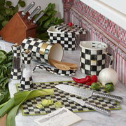 MacKenzie-Childs Courtly Check 7 Cup Measuring Cup on marble countertop, surrounded by matching checkered kitchenware, fresh vegetables, and knives, exemplifying Athens Cooks’ curated kitchen collection.