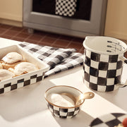 MacKenzie-Childs Courtly Check 7 Cup Measuring Cup on a kitchen counter, surrounded by matching ceramic pieces and baked goods, showcasing its stylish, hand-glazed design.