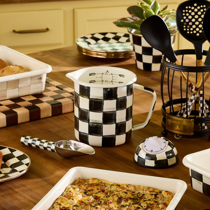 MacKenzie-Childs | Courtly Check 7 Cup Measuring Cup on a wood countertop with matching check-patterned tableware and bakeware, highlighting the pitcher’s hand-painted design and generous capacity.
