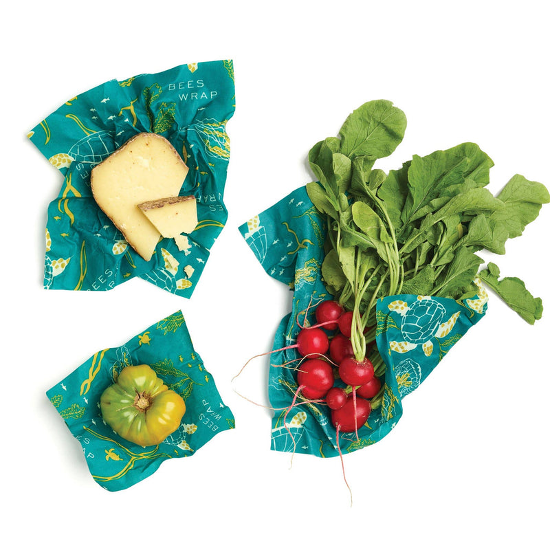 Bee's Wrap - Assorted 3 Pack - Oceans displayed with vegetables and cheese, showcasing eco-friendly, reusable food storage wraps made from organic cotton and beeswax.