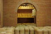 Nicola's Marketplace - Genuine Fulvi® Pecorino Romano DOP: 7 Ounces, aging in a rustic cheese cellar with shelves full of cylindrical cheese wheels in Lazio, Italy.