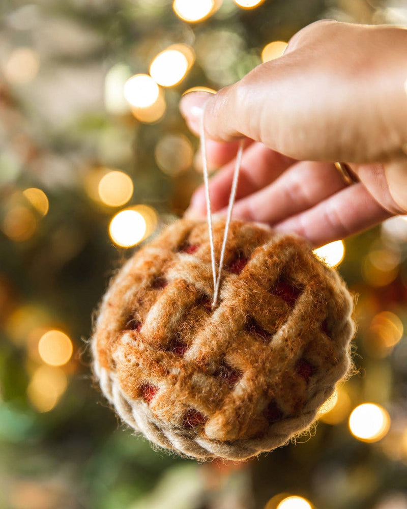 Farmhouse Pottery - Granny's Apple Pie Felt Ornament held in hand, showcasing a handcrafted wool pie design, suspended by twine, perfect for holiday decoration.