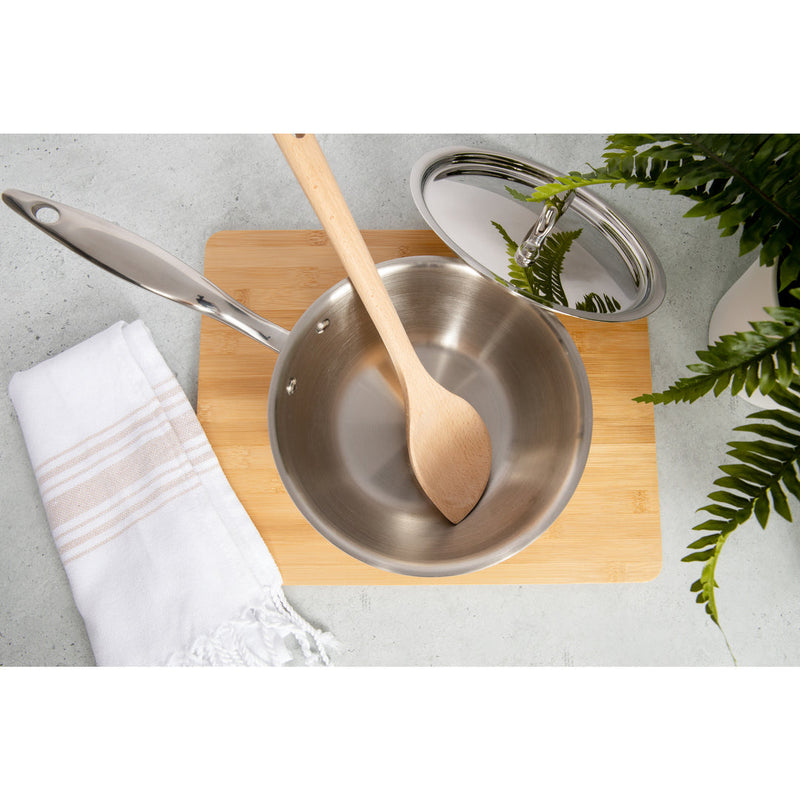 Heritage Steel 2 quart titanium saucier with lid and wooden spoon on a cutting board, ideal for cooking