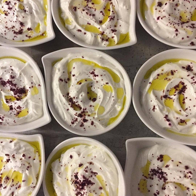 Burlap & Barrel - Cured Sumac: Ramekins with labneh topped with olive oil and cured sumac from Gaziantep, Turkey, highlighting its bright, sour flavor.