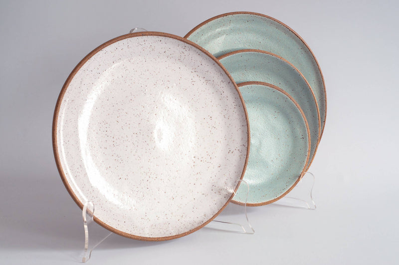 RachaelPots - Dinner Plate: Yellow, featuring a creamy-white speckled design, hand-thrown stoneware, displayed on acrylic stands, perfect for enhancing any table setting.
