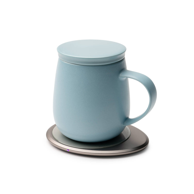 OHOM - Ui 3 Self-heating Mug Set: Moonmist Blue, featuring a sky-blue ceramic mug with lid on an electric warmer, ideal for maintaining drink temperature.
