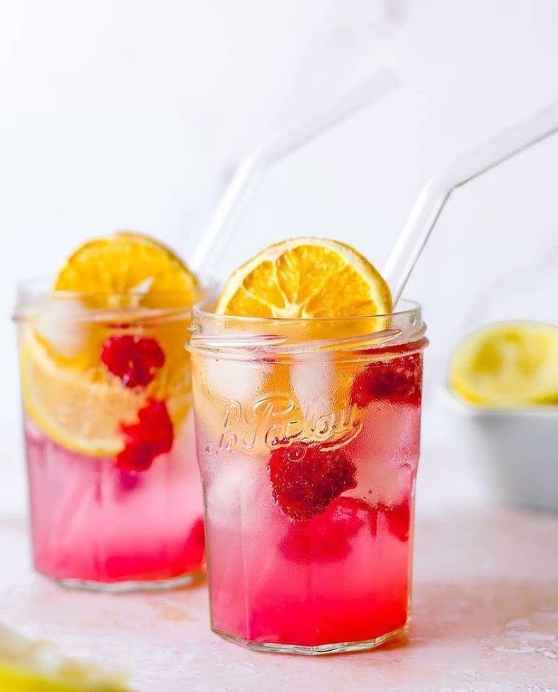 Le Parfait - 324ml French Jam Jar Faceted Jelly Glass with Metal Twist Lid, featuring pink raspberry-citrus lemonade, raspberries, citrus slices, and ice, with glass straws.