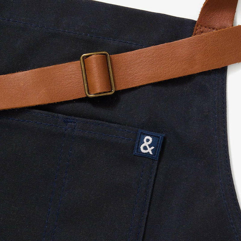 Hedley & Bennett | Essential Waxed Canvas Aprons - Montana, featuring a durable design with an adjustable leather neck strap, navy waist tie, and multiple pockets.