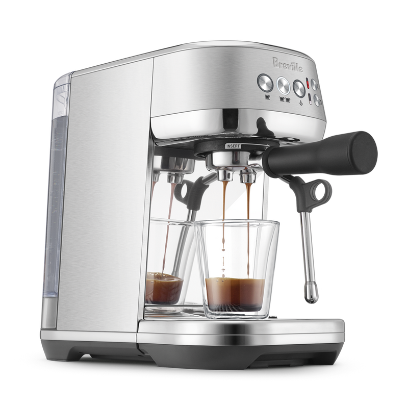 Breville | Bambino Plus espresso machine pulling two shots into glass cups, featuring a portafilter, steam wand, and control panel for precise home brewing.