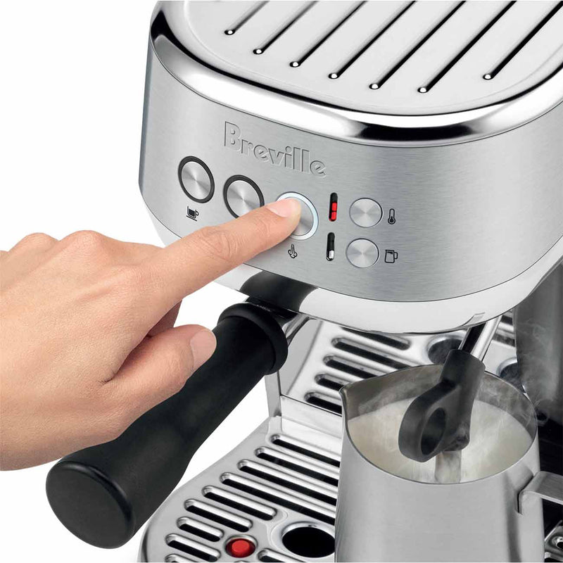 Breville | Bambino Plus espresso machine with a user pressing a control button, frothing milk with the steam wand, showcasing professional cafe features.