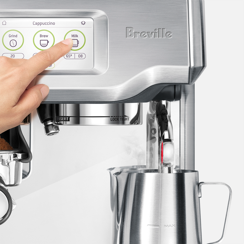 Breville | Barista Touch espresso machine with touchscreen, showing a hand selecting Milk while frothing milk, alongside a loaded portafilter, at Athens Cooks.