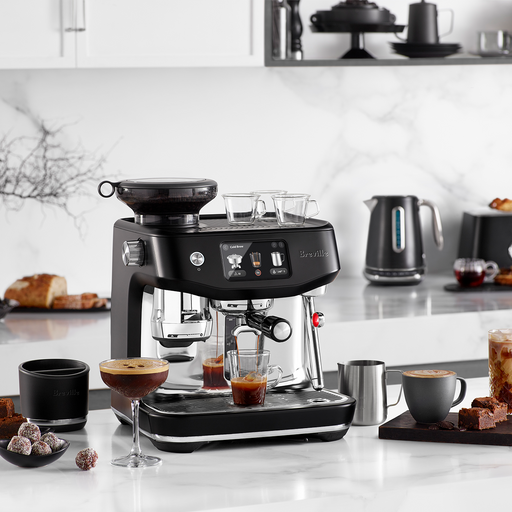 Breville | The Oracle Jet, Black Truffle espresso machine on countertop with espresso cups, milk frother, latte art, cocktail, and gooseneck kettle, showcasing café-quality brewing.