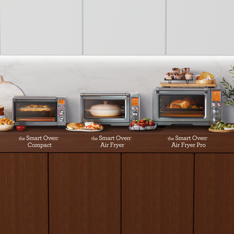Breville | Smart Oven Air Fryer Pro showcasing a whole chicken, flanked by two other models with fries and casserole, on a modern kitchen countertop.