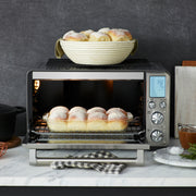Breville | Smart Oven Air Fryer Pro with dinner rolls baking inside, showcasing its digital display and controls, epitomizing Athens Cooks’ curated kitchen excellence.