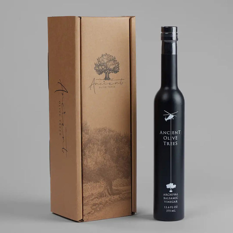 Ancient Olive Trees | Balsamic Vinegar bottle beside its packaging, featuring a helicopter logo and tree drawing, highlighting premium, barrel-aged vinegar from Athens Cooks.