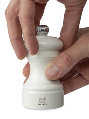Peugeot | Bistro Salt Mill, Ivory, in hand with twisting action, showcasing its classic beech wood design and adjustable steel grinding mechanism for salt crystals.