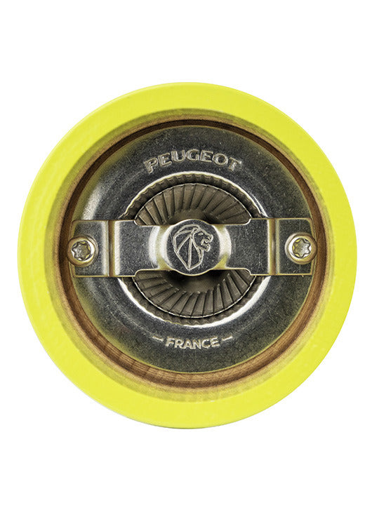 Peugeot | Bistro Salt Mill in Green Pistachio, showcasing its iconic conical metal burr mechanism, viewed from above, set within a yellow-painted wooden housing.
