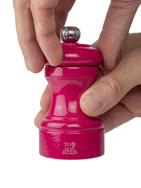 Peugeot | Bistro Salt Mill, Candy Pink, shown in hands while being twisted to grind, highlighting its ergonomic grip and durable steel mechanism.