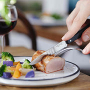 Opinel | Bon Appétit No.125 knife slices pork tenderloin on a plate with steamed vegetables, showcasing its durable, dishwasher-safe design ideal for everyday use.