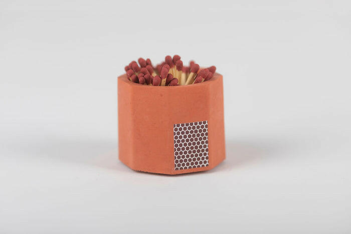 Close-up of the Tenn Prairie Match Holder, a hand-poured concrete vessel with a cork bottom, containing blue matches and a striker pad for easy lighting.