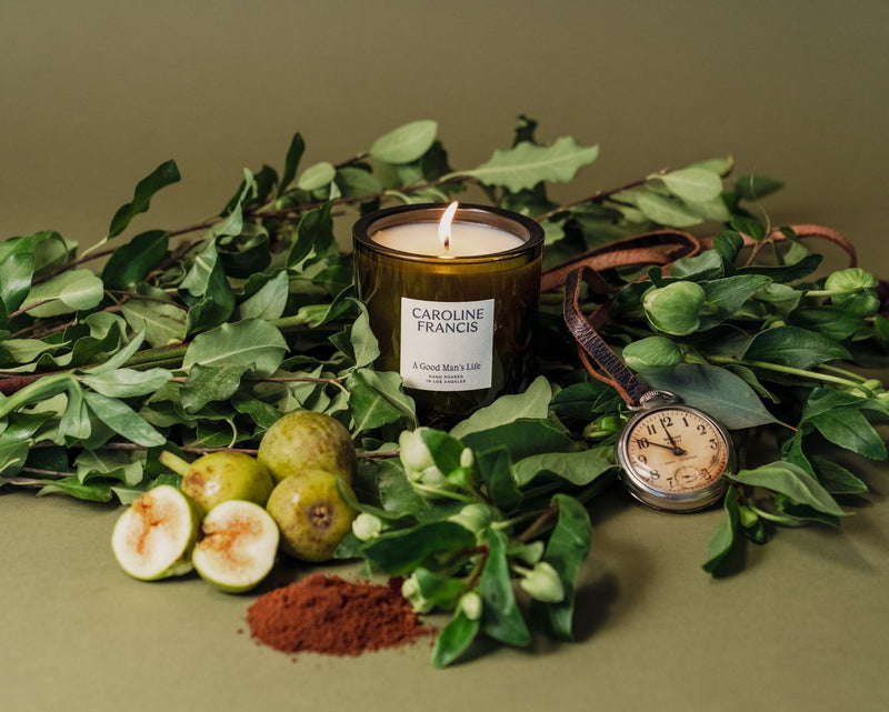 Caroline Francis | A Good Man's Life candle, hand-poured coconut soy wax in a glass container, accompanied by a pocket watch, on a kitchen table.