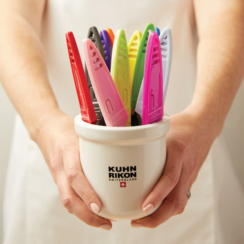 Kuhn Rikon Colori Paring Knife (Marshmellow) displayed in a ceramic pot with colorful clips, ideal for precise peeling and slicing tasks with its sharp Japanese stainless steel blade.