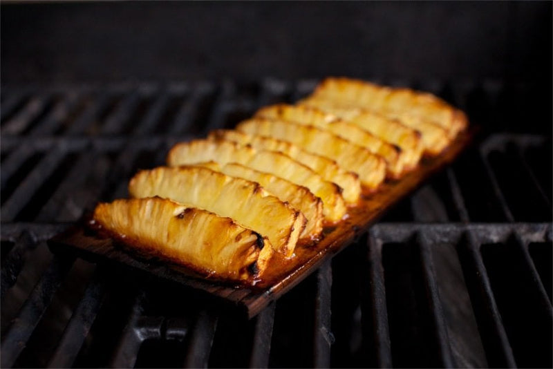 Wildwood Grilling | Cedar Grilling Planks with pineapple slices on a grill, ideal for infusing food with a smoky Pacific Northwest flavor.