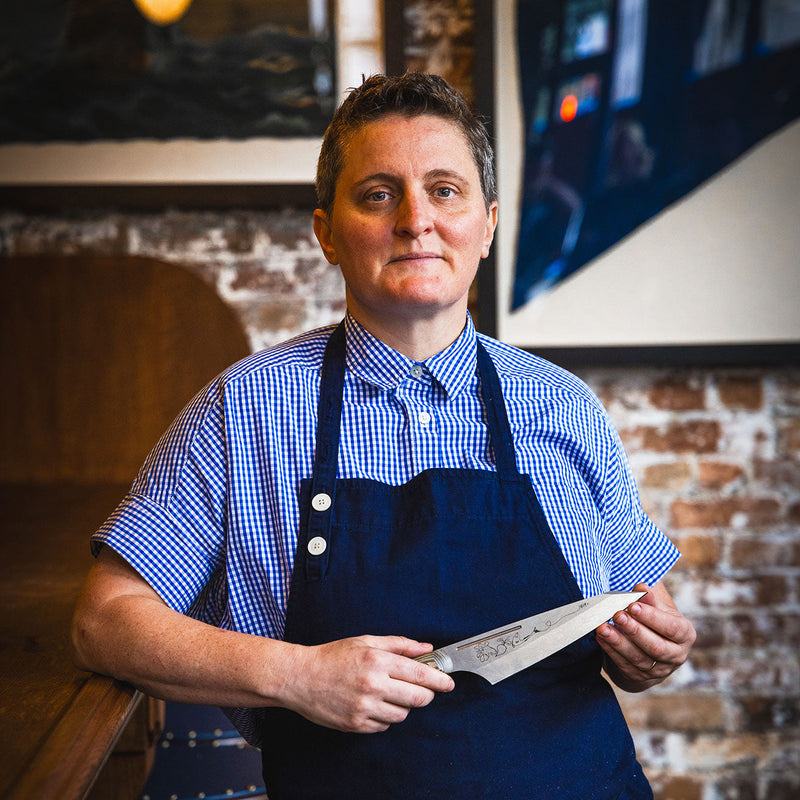 Person presenting the Messermeister | Chef April Bloomfield Chef's Knife, 6.5 inches, in a kitchen setting, highlighting its design and craftsmanship.
