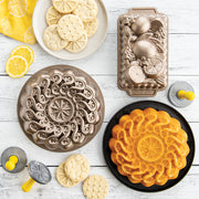 Nordic Ware | Citrus Cookie Stamps set with citrus-inspired designs and yellow hardwood handles, surrounded by cookies and baking pans.