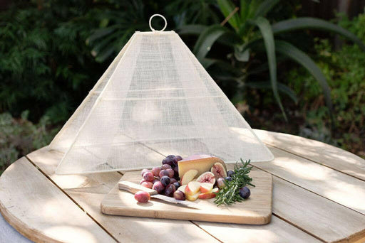 NEEPA HUT | Collapsible Woven Food Tent - Rose Pink, elegantly covering fruit and cheese platter outdoors, showcasing its unique pentagon shape and foldable design for easy transport.