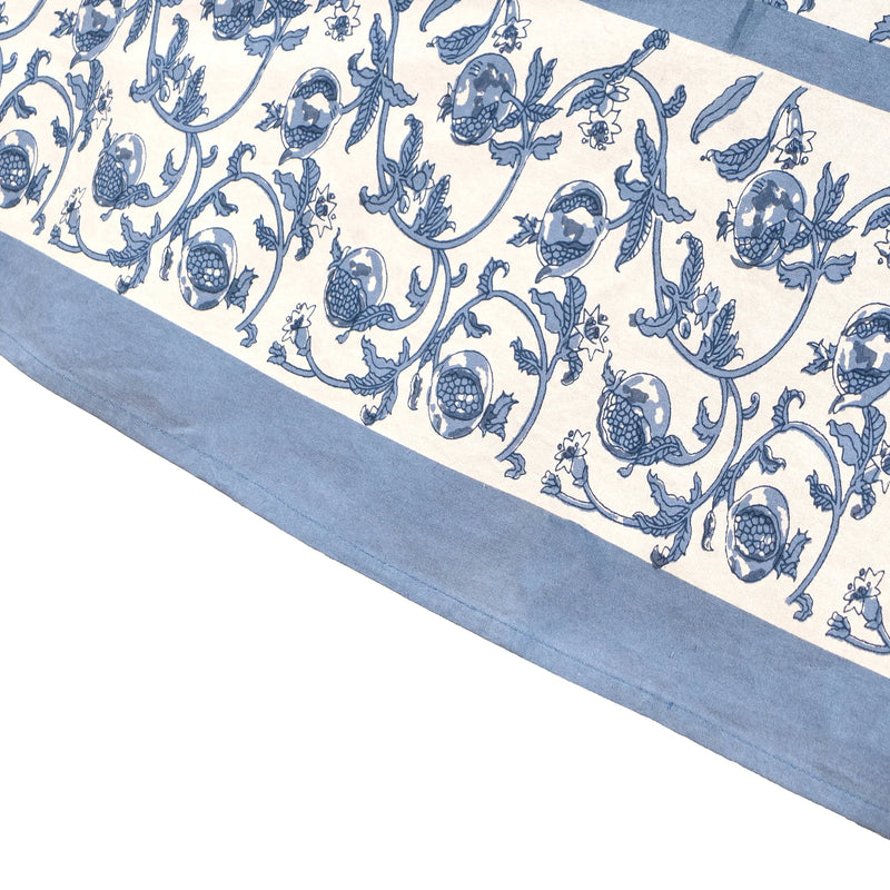 Close-up of the Caravan Home 71 x 106 Granada Cornflower Blue Tablecloth, showcasing intricate floral patterns with cornflower blue pomegranates on a white background.