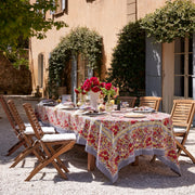 Caravan Home | 71 x 106 Red & Grey Tablecloth elegantly drapes an outdoor dining table, surrounded by chairs and decorated with a vase of red flowers.