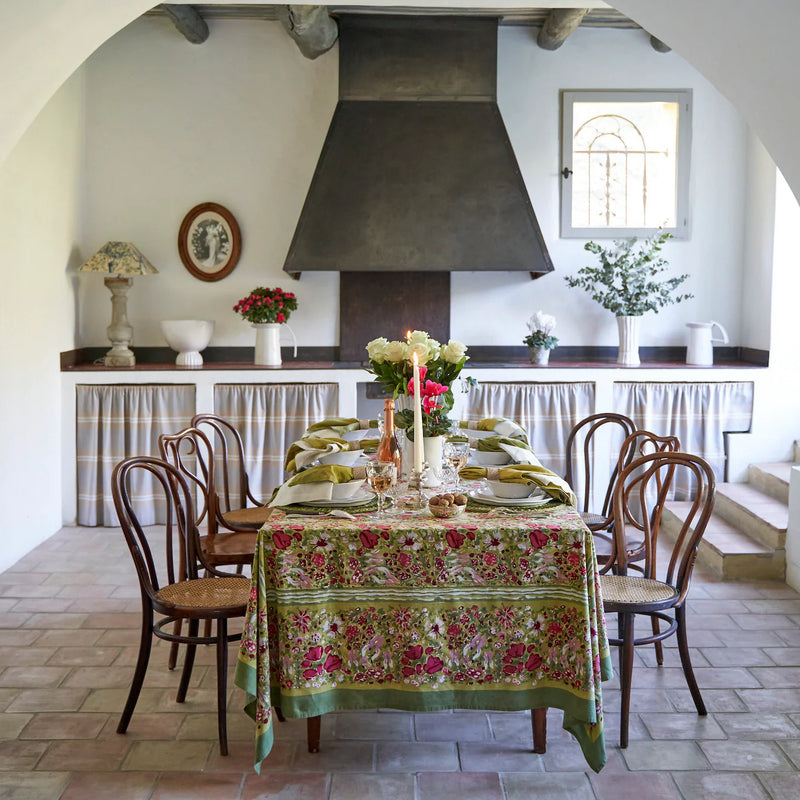 Caravan Home | 71 x 71 Red & Green Tablecloth elegantly drapes a dining table with floral settings, complementing the Jardin collection's lush, artisan-crafted design.