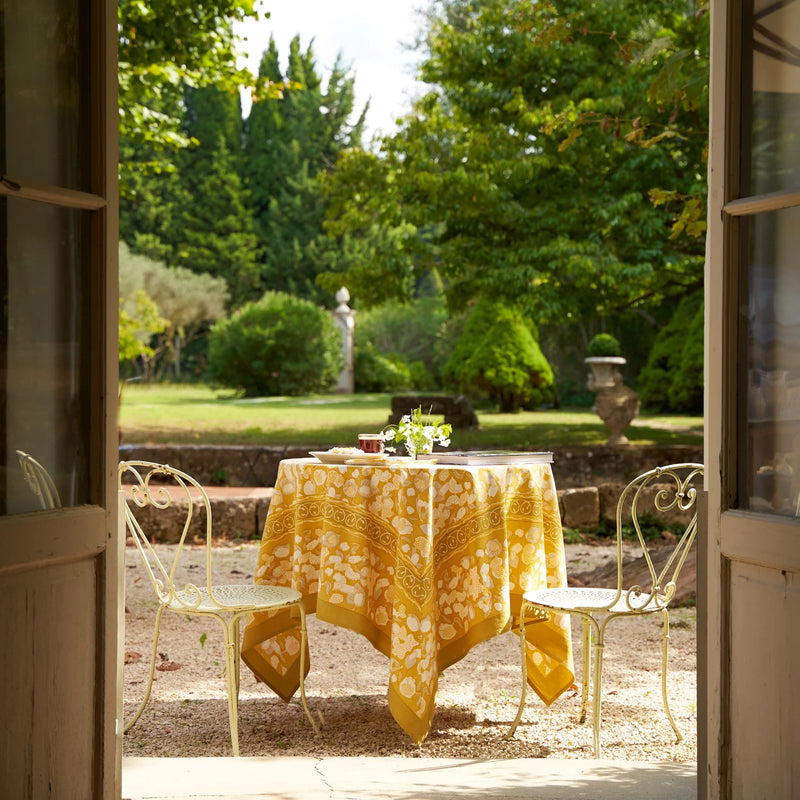 Caravan Home | 59 x 86 Forest Harvest Grey & Mustard Tablecloth set on an outdoor table, showcasing intricate fruit and foliage design.