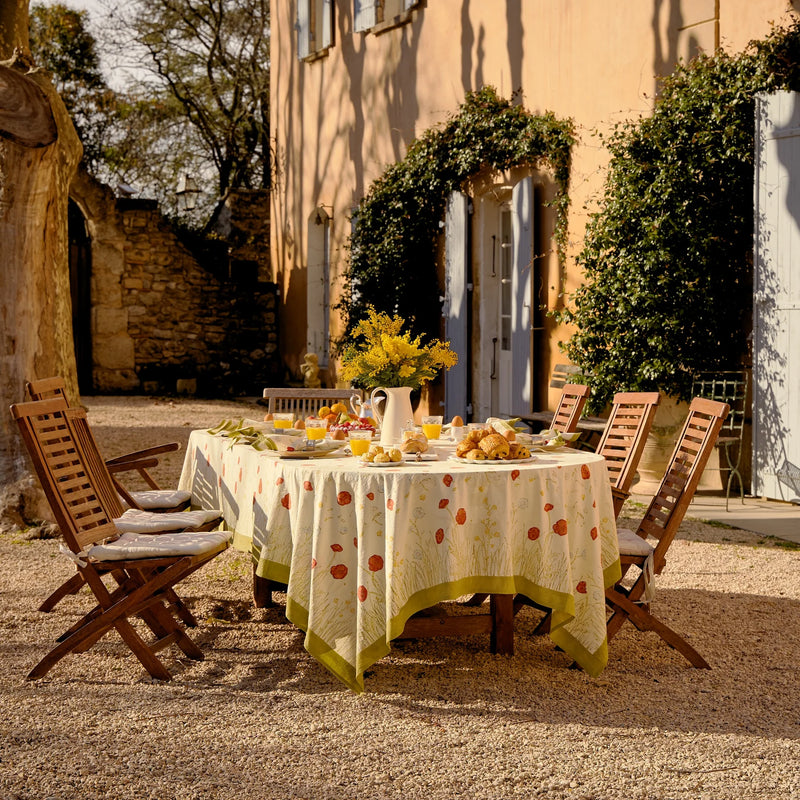 Outdoor setting featuring the Caravan Home 71 x 106 Springfields Multi French Tablecloth with floral patterns on a dining table, surrounded by wooden chairs with cushions.