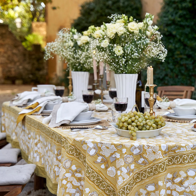 Caravan Home 59 x 86 Forest Harvest Tablecloth featuring entwined foliage and fruits, styled on a table with grapes and flowers.