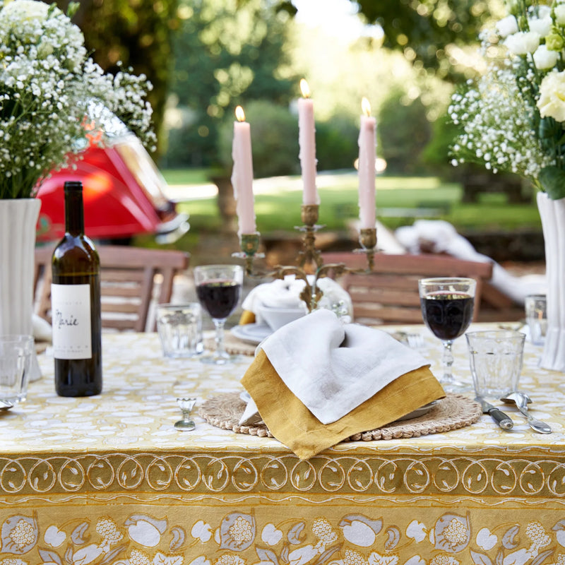 Caravan Home 21 x 21 Dijon Everyday Napkins Set of 4 displayed on a table with candles and wine, highlighting their oversized, hand-dyed linen texture.