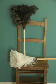 Earth & Nest | Feather Duster displayed on a chair, featuring premium natural feathers and a turned blond wood handle with a leather strap.