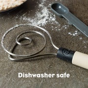 Brod & Taylor Dough Whisk on table with measuring spoon, designed for efficient dough mixing, available at Athens Cooks, a specialist kitchen store.