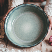Emile Henry 175th Anniversary Pie Dish in Blue/Sable — hands cradling the dish, highlighting the mineral blue interior and scalloped rim