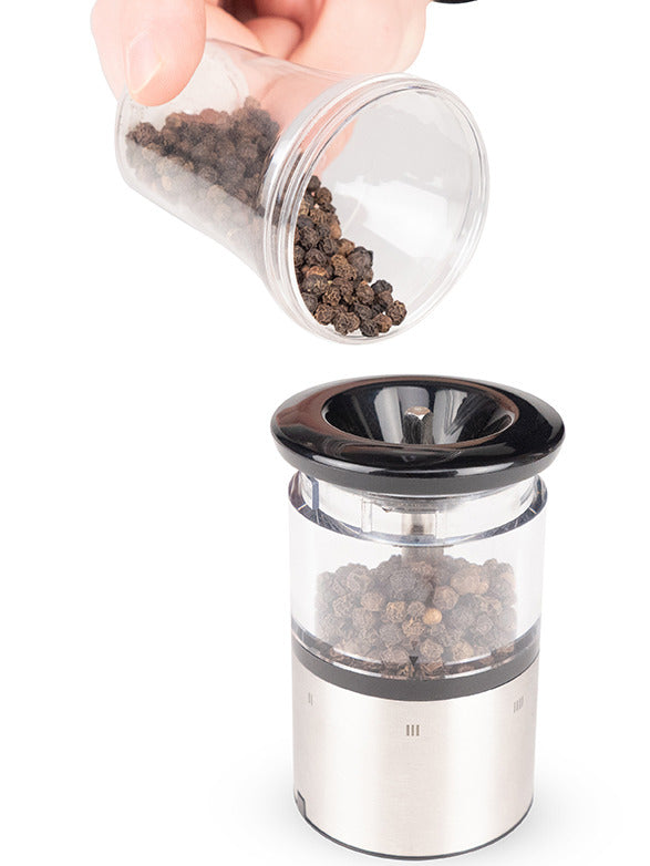 Peugeot Elis Sense Pepper Mill, 8, being filled with black peppercorns, showcasing its sleek stainless steel and acrylic design, ideal for precise, high-tech grinding.