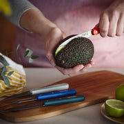 Close-up of an Opinel paring knife slicing an avocado on a cutting board, showcasing the Opinel | Essential Small Kitchen Knife Sets, Loft collection.